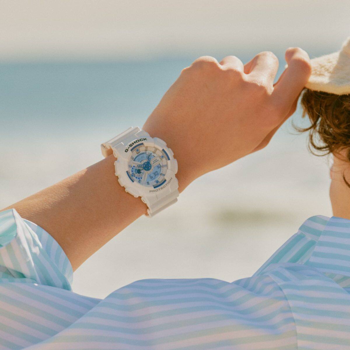 GA-110HDS-7AER al polso di una persona che indossa un top a righe bianche e blu