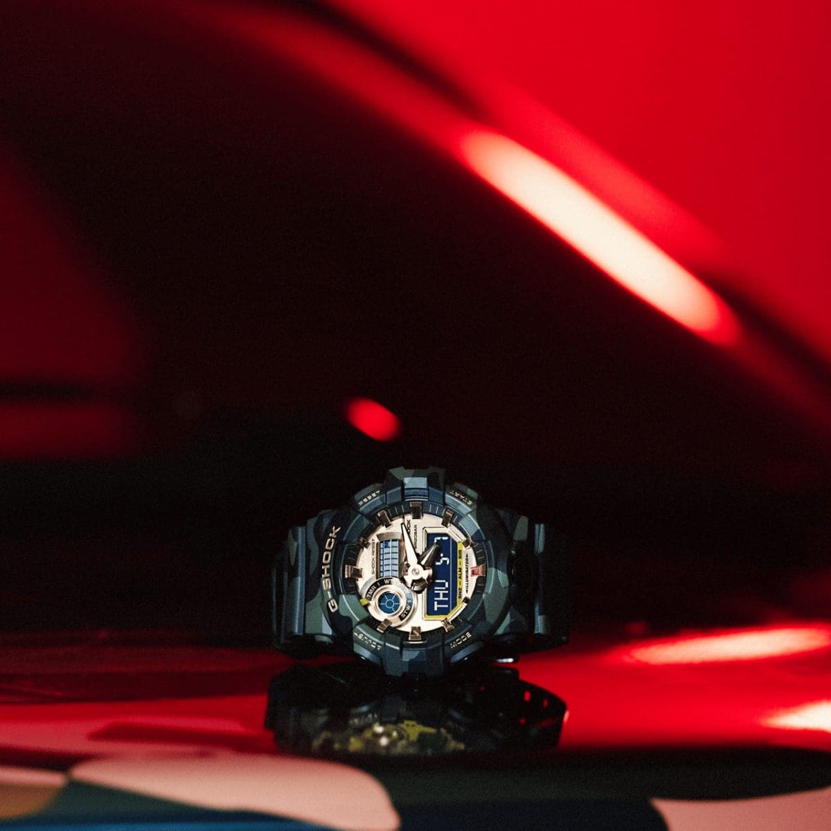 L'orologio da polso GA-700CMG-3AER è appoggiato su una superficie rossa lucida