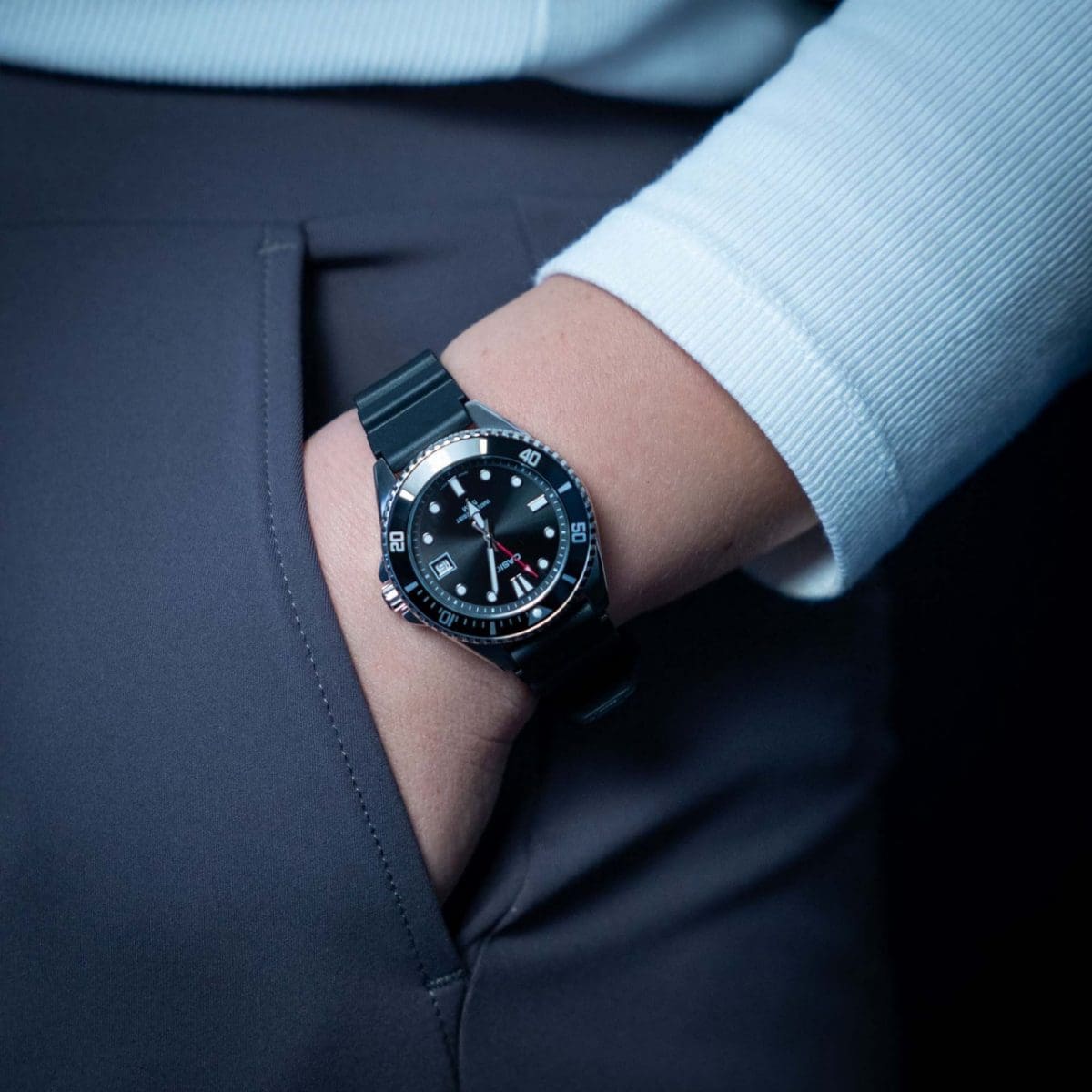 Primo piano dell'orologio da polso MDV-10-1A1V con cinturino nero e cassa nera al polso di una donna con la mano nella tasca dei pantaloni.
