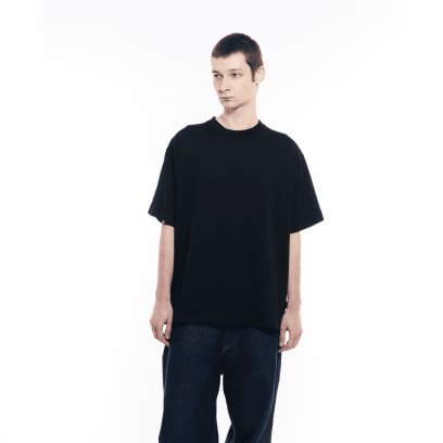 Een man in een donkere spijkerbroek draagt ​​een GXFAB T-shirt.