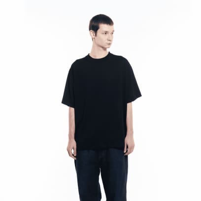 Een man in een donkere spijkerbroek draagt ​​een GXFAB T-shirt.