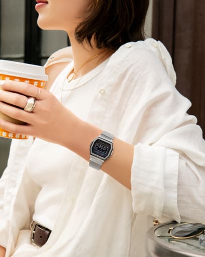 Vrouw met een zilveren A1000M-1B en ringen, een koffiemok in de hand en een wit overhemd