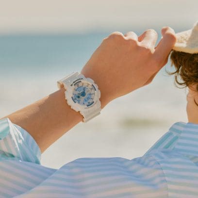 GA-110HDS-7AER om de pols van een persoon die een blauw-wit gestreepte top draagt