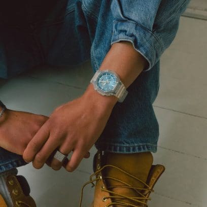 De GA-2100BM-7A2 om de pols van een man die een spijkerjasje draagt in combinatie met een spijkerbroek. 