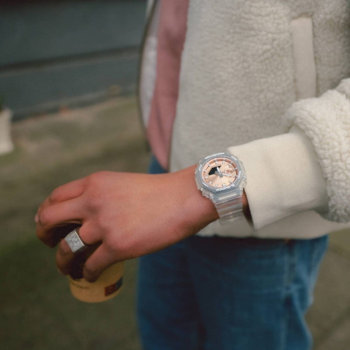 Een man draagt de GA-2100BM-7A5 om zijn pols en heeft een pastelkleurig T-shirt en een wit jasje aan.