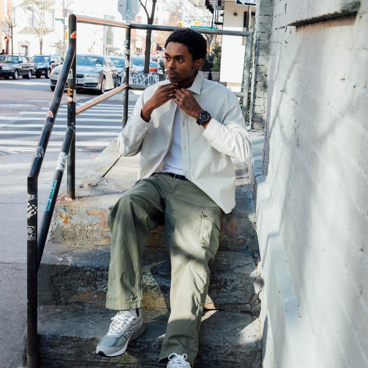 Een man zit op de trap en knoopt zijn witte overhemd dicht. Hij draagt ​​de G-SHOCK GD-010-1A1 om zijn pols