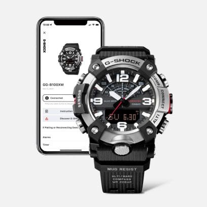 De G-SHOCK GG-B100XM-1AER naast een smartphone waarvan het scherm ook de GG-B100XM-1AER weergeeft.