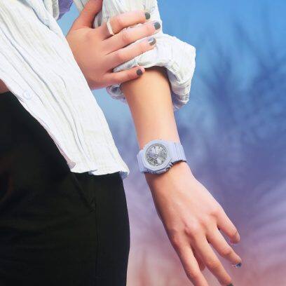 Halflange opname van een vrouw met een witte blouse opgerold en met het lilakleurige GMA-P2100SG-2AER polshorloge van G-SHOCK om haar pols