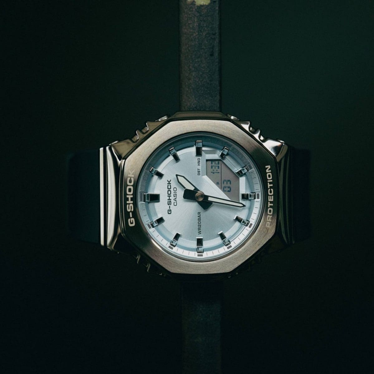 De GM-S2110-2AER  hangt aan een zwarte metalen stang voor een zwarte achtergrond. 