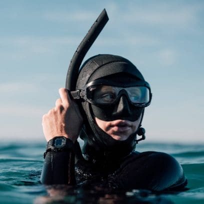 Een duiker in het water draagt ​​een zwart wetsuit en de zwarte GW-5000HS-1 om haar pols