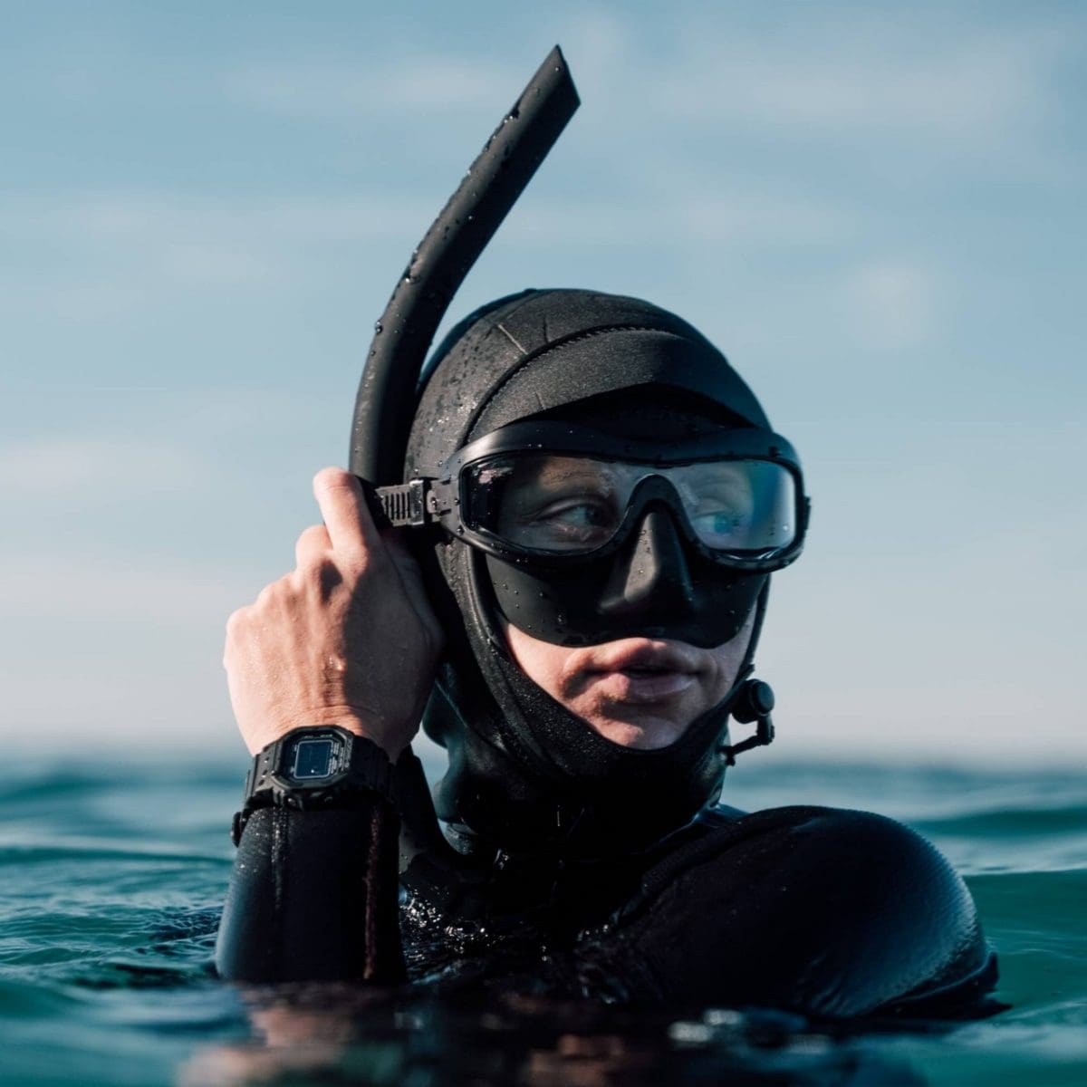 Een duiker in het water draagt ​​een zwart wetsuit en de zwarte GW-5000HS-1 om haar pols