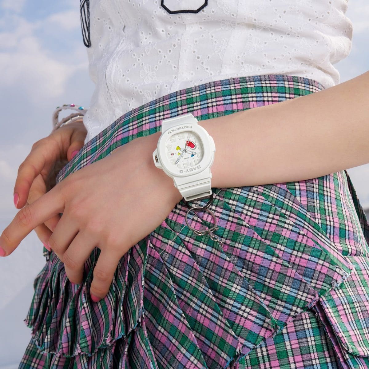 BGA-10-7AER no pulso de uma mulher vestindo saia xadrez e blusa branca