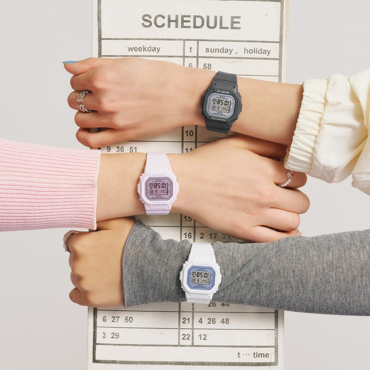 Três mulheres usam relógios de pulso BABY-G nas cores branca, rosa e cinza, e exibem alternadamente um calendário.