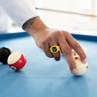 O DWN-5600-9ER no dedo anelar de um homem que está tocando uma bola de bilhar