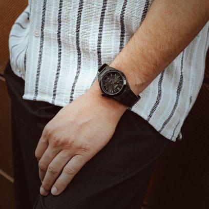 O EFK-100XPB-1AER no pulso de um homem vestindo uma camisa listrada branca, preta e bege