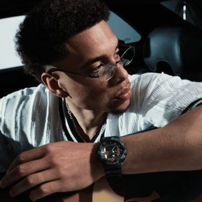 Um homem com uma camisola clara e óculos usa o relógio de pulso GA-700CMG-3AER da G-SHOCK no pulso