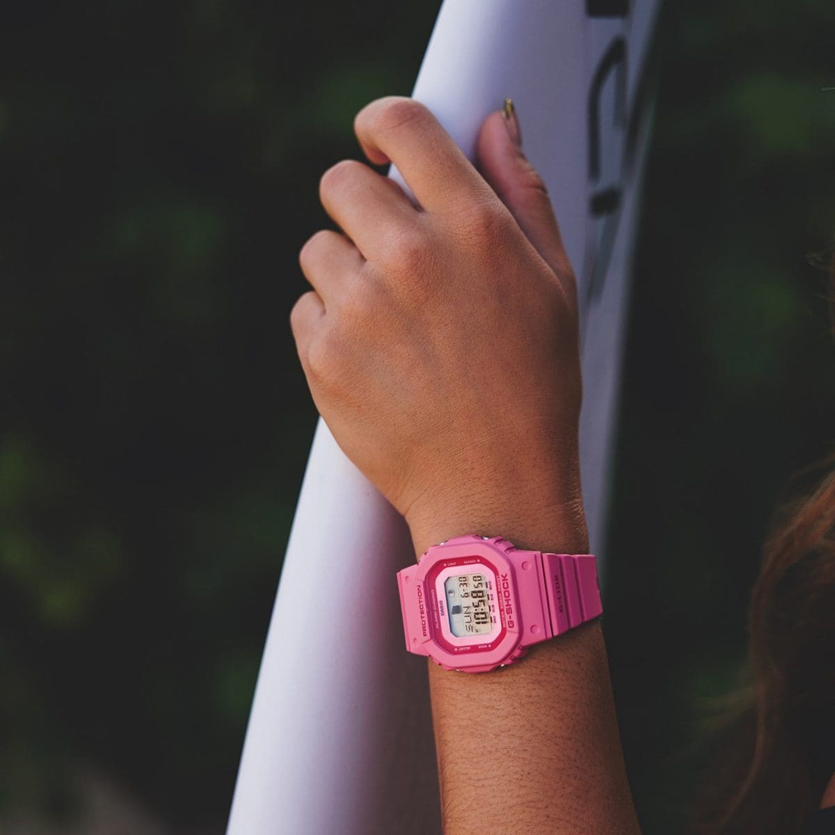 GLX-S5610-4 no pulso de uma pessoa segurando uma prancha de surfe