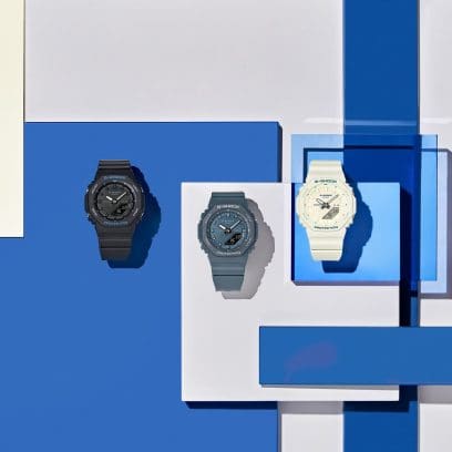 Três modelos nas cores preto, azul marinho e branco marfim estão dispostos lado a lado em quadrados azuis de cores diferentes.