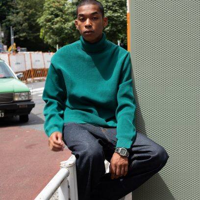 Homem sentado na cerca, com a mão na coxa e usando o gmw-B5000D-3 no pulso