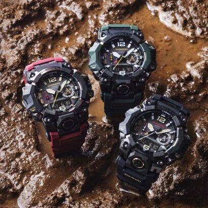 Três modelos do relógio de exterior CASIO Master of G Mudmaster na lama, à esquerda o modelo com bracelete vermelha, ao centro o modelo com bracelete verde e à direita o modelo com bracelete preta