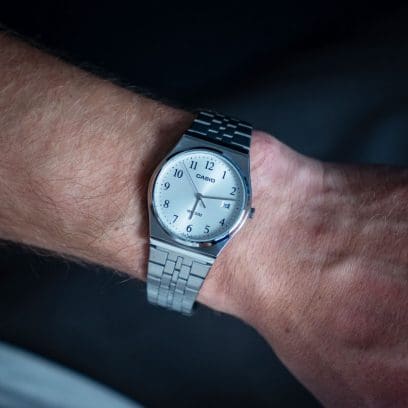 Grande plano do relógio de pulso MTP-B145D-7BV com bracelete prateada no pulso de um homem.