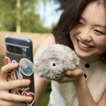 Gold Moflin AI robot in the hand of a smiling woman denoting companionship