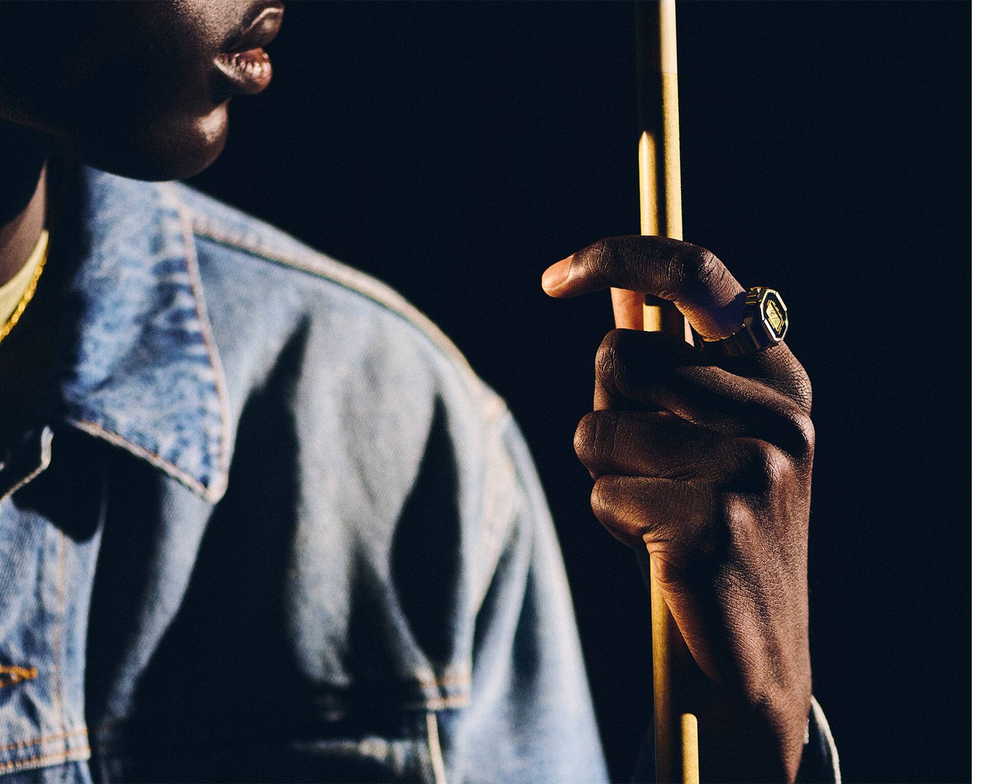 صورة رجل يمسك عصا البلياردو وساعة CRW-001G معلّقة بيده.