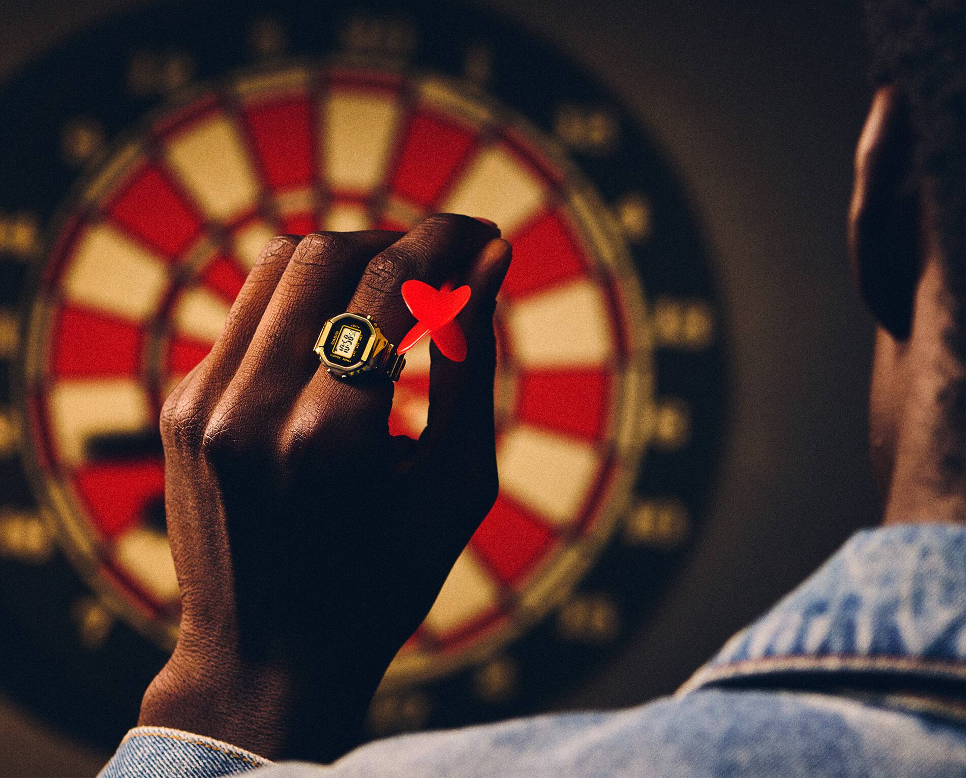 صورة رجل يرتدي ساعة CRW-001G في إصبعه ويمارس لعبة رمي السهام.