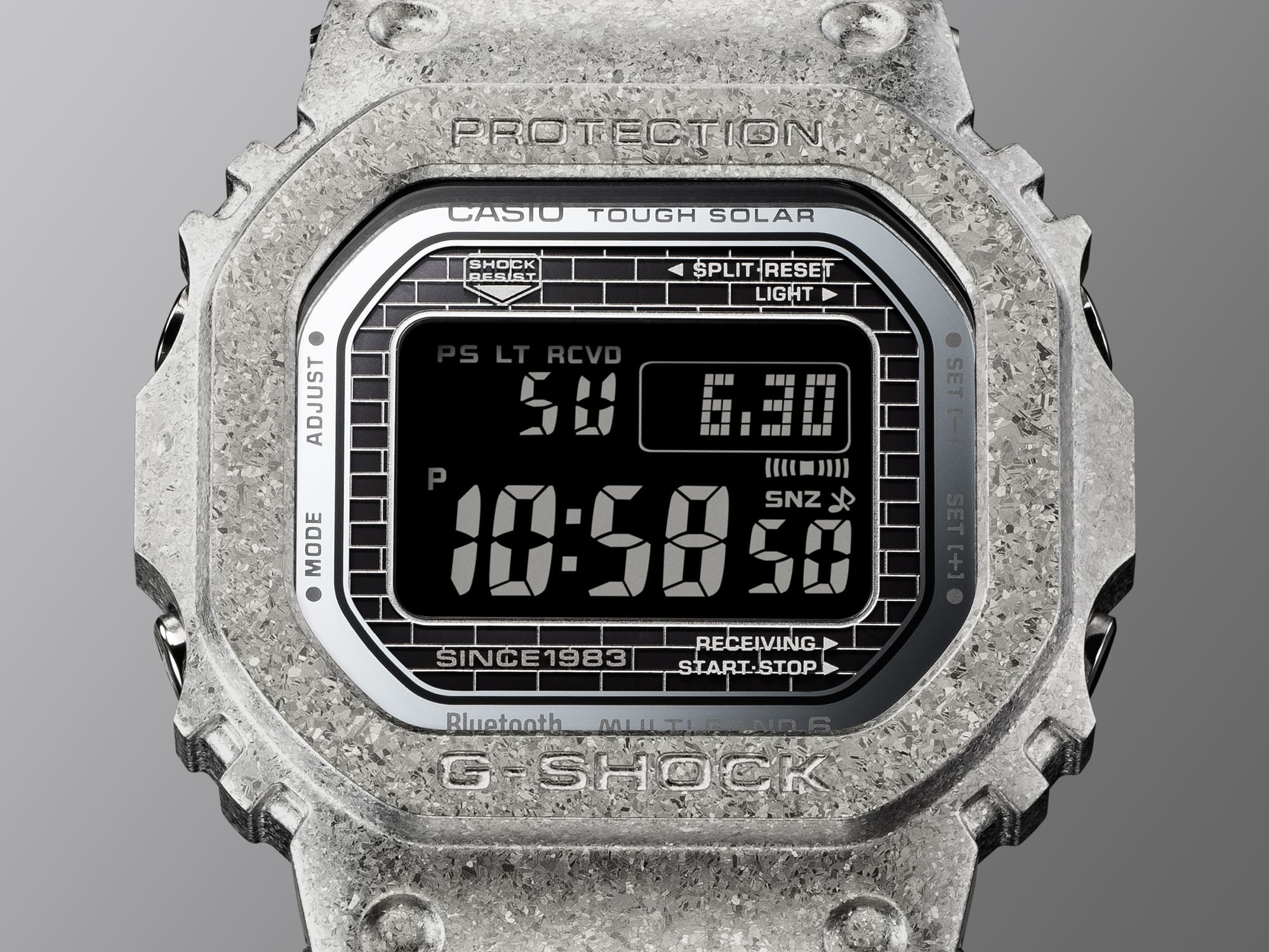 Nahaufnahme des Displays der Casio G-Shock GMW-B5000PS-1 Jubiläumsuhr mit Backsteinmuster und silber-glänzendem Rahmen