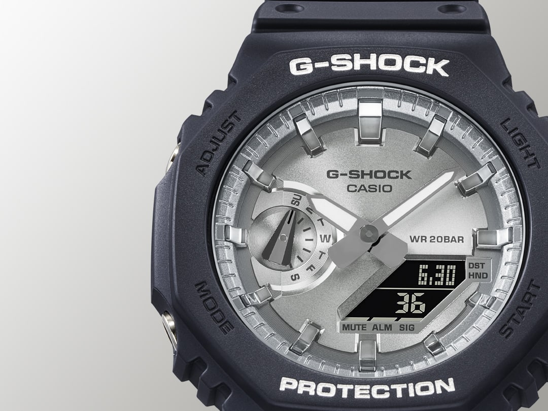 Großaufnahme des silberfarbenen Zifferblatts und der mattschwarzen Lünette der Casio G-Shock GA-2100SB Hybridarmbanduhr