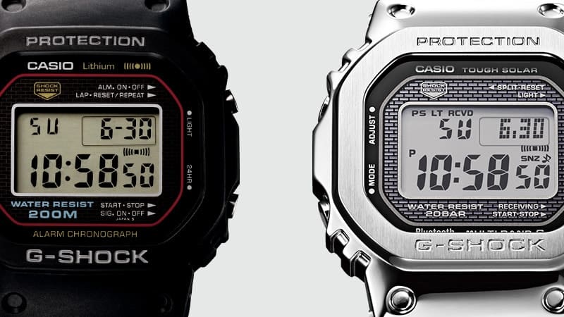 Nahaufnahme des ersten schwarzen G-Shock Digitaluhr-Models neben der silberfarbenen G-Shock GMW-B5000