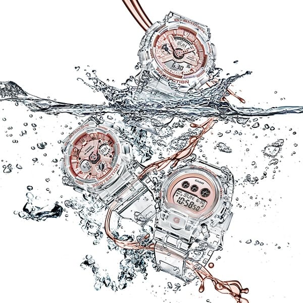 Die Casio G-Shock GMA-S120SR-7A Damenuhr fällt in spritzendes Wasser, zusammen mit zwei anderen Armbanduhren, die ebenfalls transparente Armbänder und roségoldene Zifferblätter haben