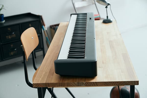Das kompakte, schwarze Compact Digital Piano CDP-S110BK liegt auf einem einfachen Holzschreibtisch