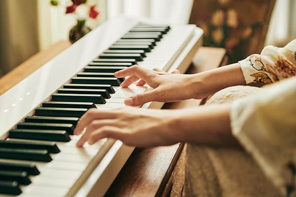 Nahaufnahme auf die Tastatur des weißen Privia PX-S1100WE Digitalpianos, während jemand Klavier spielt