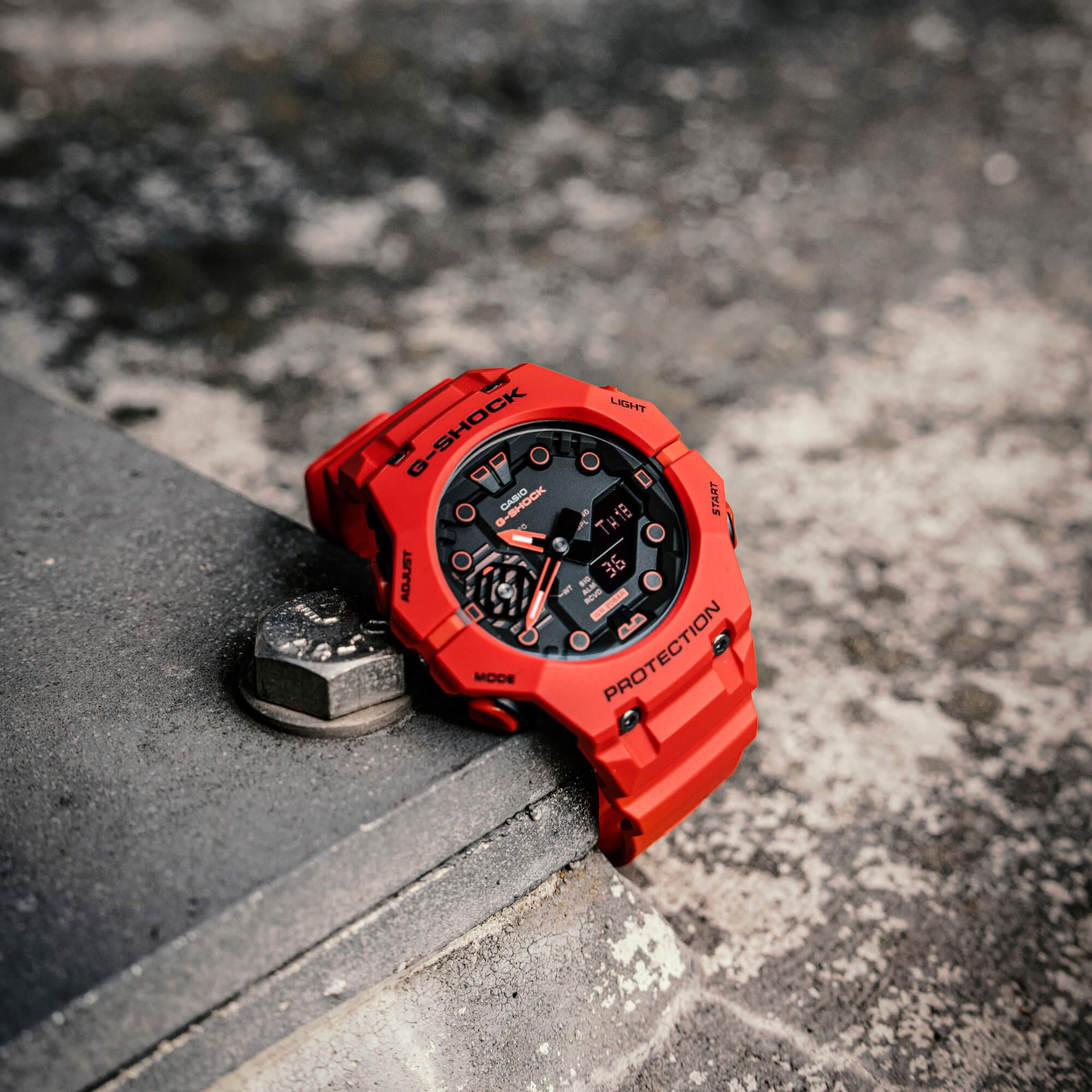 Die G-Shock Uhr GA-B001-4AER in rot mit schwarzem Zifferblatt auf Betonuntergrund.