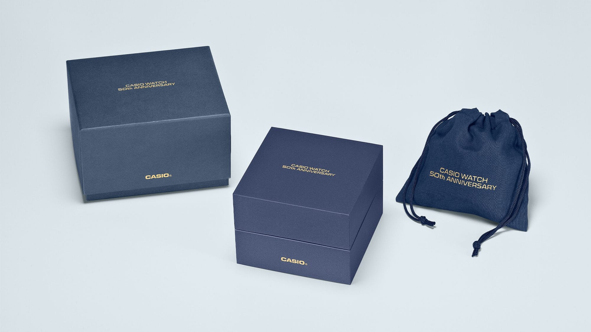 The blue packaging box of the Casio TRN-50SS-2A next to the blue outer packaging and blue fabric bag. All packaging parts bear the gold-coloured lettering: Casio Watch 50th Anniversary
