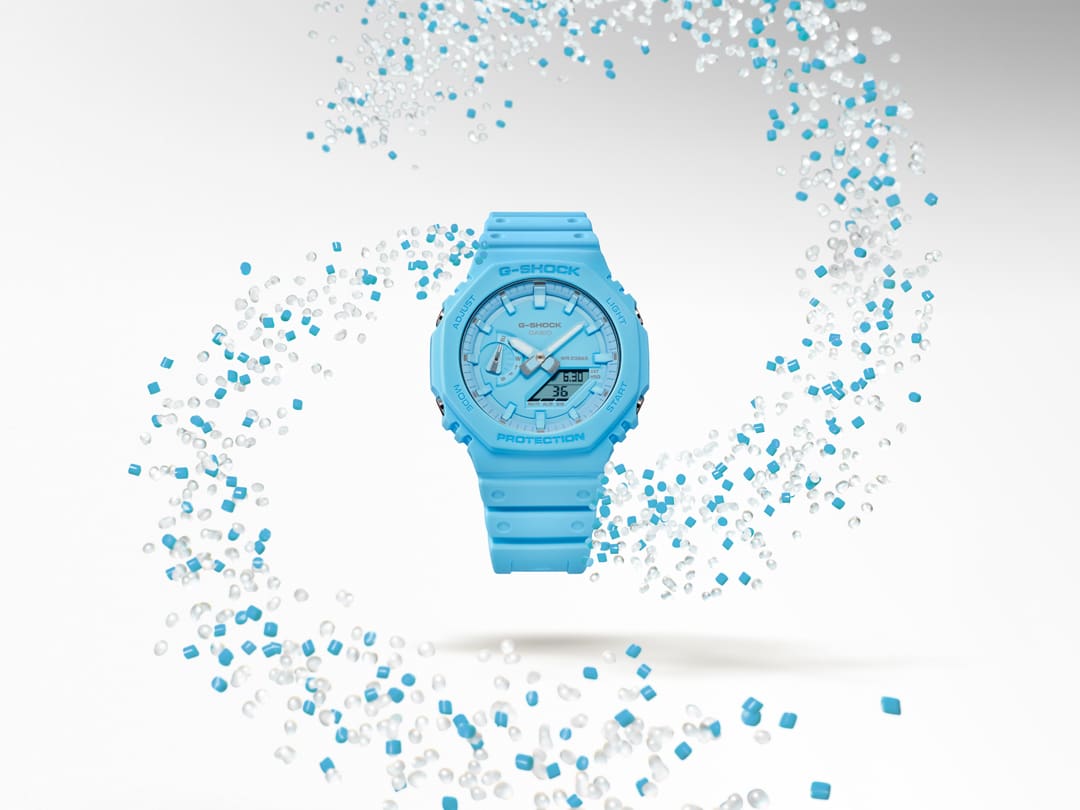 The GW-B5600CD-9 wristwatch surrounded by a swirl of transparent and turquoise-coloured resin granules
