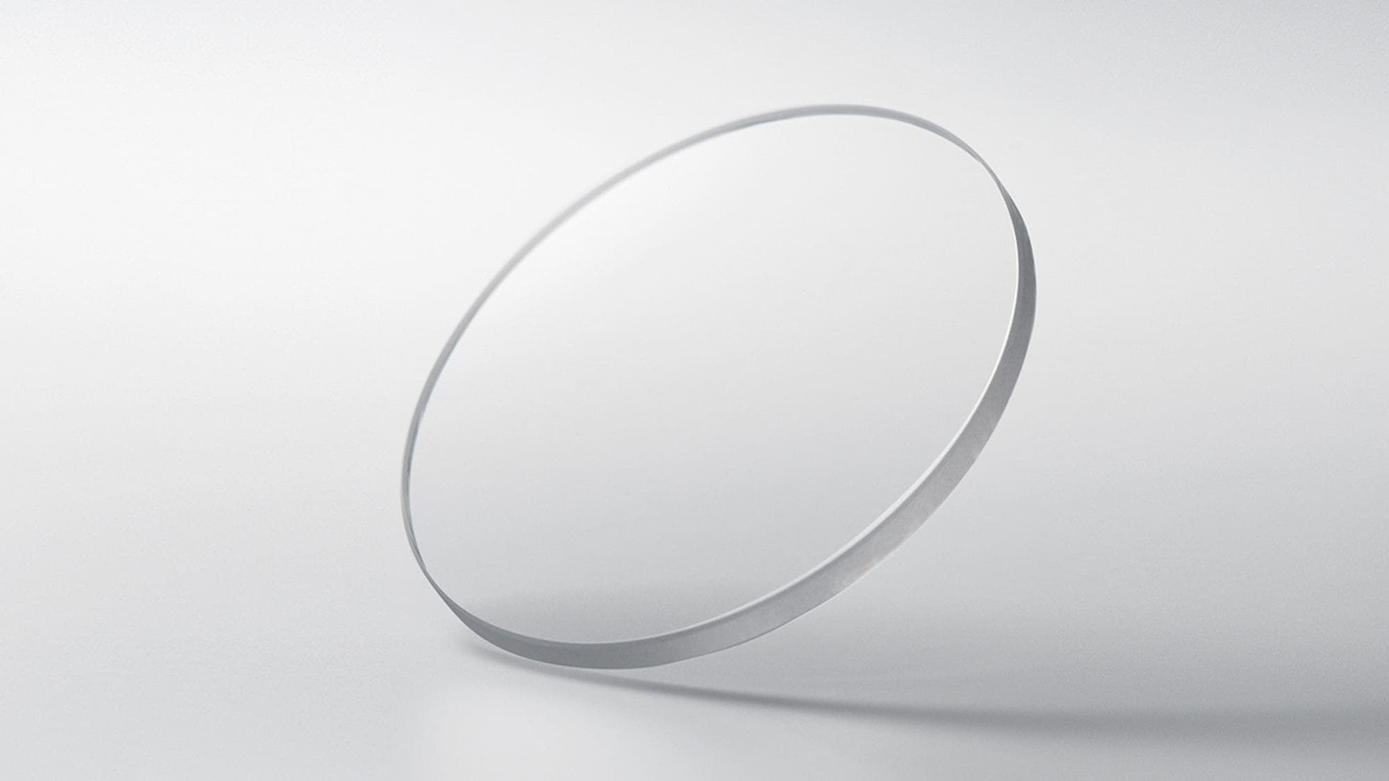 A round sapphire crystal disc against a light grey background