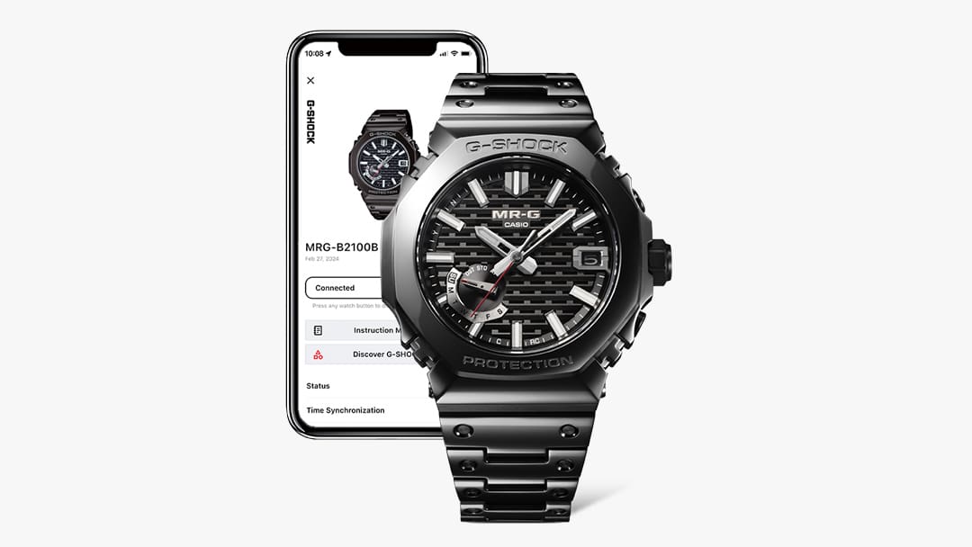 The MRG-B2100B wristwatch in black next to a smartphone with the CASIO Watches app open.