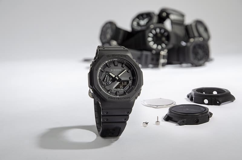 A black Casio G-Shock women's watch in front of the individual parts that make it up