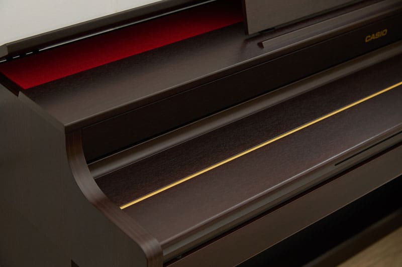 Close-up of a brown CASIO AP-300 digital piano with the keyboard cover closed. 