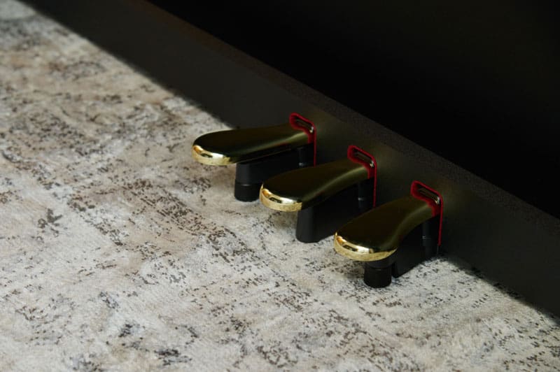 Close-up of the three gold-coloured pedals of a black CASIO digital piano AP-300