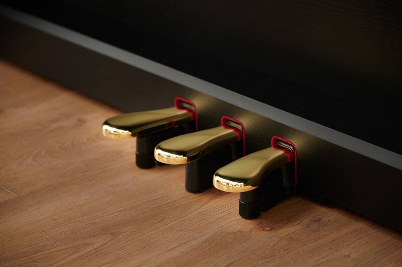 Close-up of the three gold-coloured pedals of a black CASIO AP-550BK digital piano