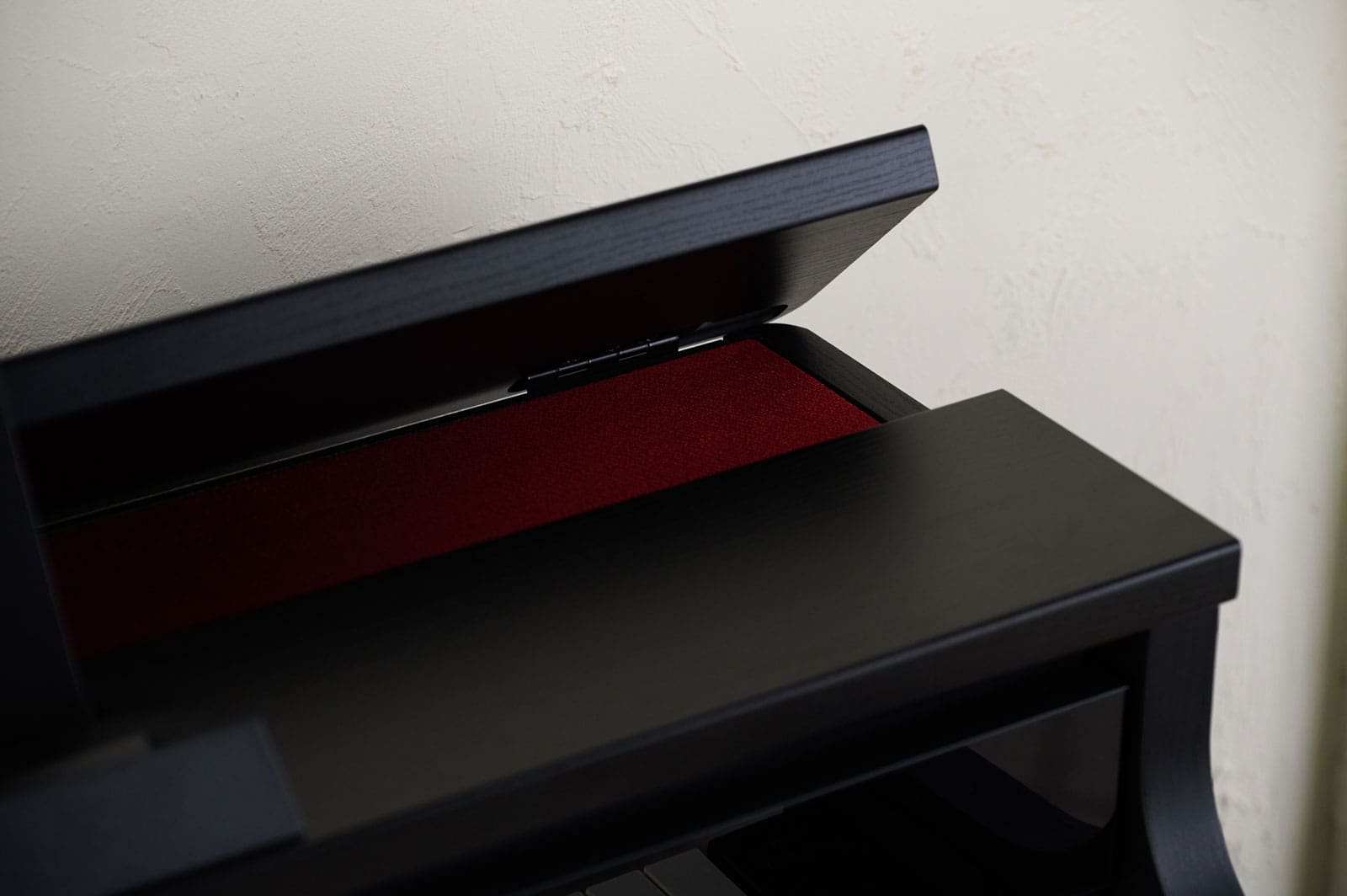 Close-up of the open upper piano lid of the black CASIO AP-750 digital piano with a view of the dark red interior