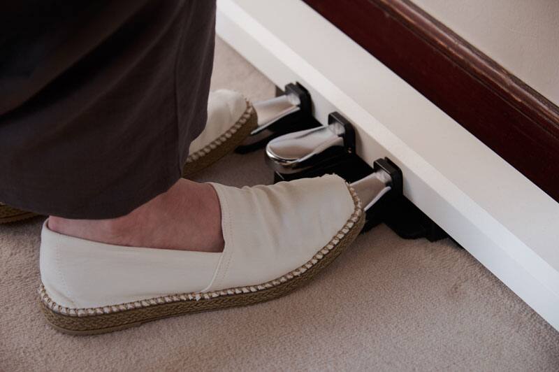 Two women's feet in light-coloured espadrilles operate the silver-coloured pedals of a white AP-S200WE digital piano