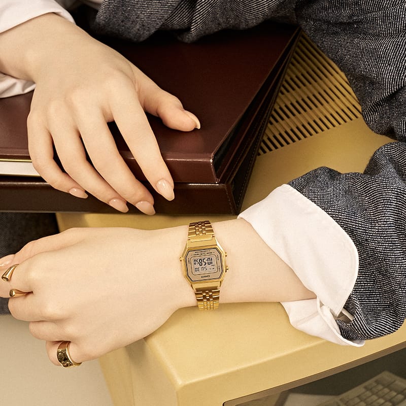 Photo of a woman's hand wearing a gold watch.