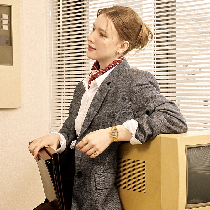 Image of a woman wearing a jacket and a gold watch and holding a file.