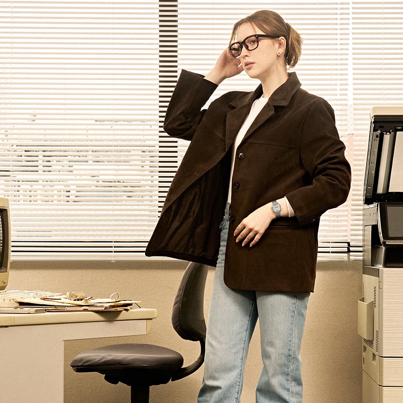 Image of a woman wearing a silver watch standing near the desk.
