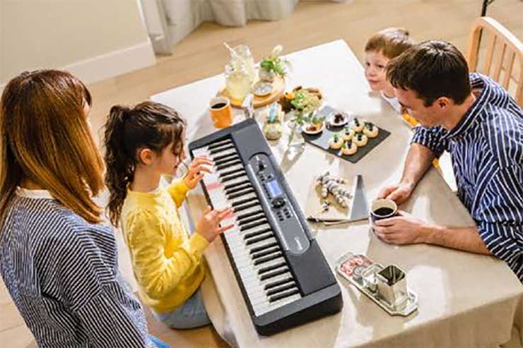 Family at a table while child plays Casiotone LK-S450 with lighted keys Family at a table while child plays Casiotone LK-S450 with lighted keys