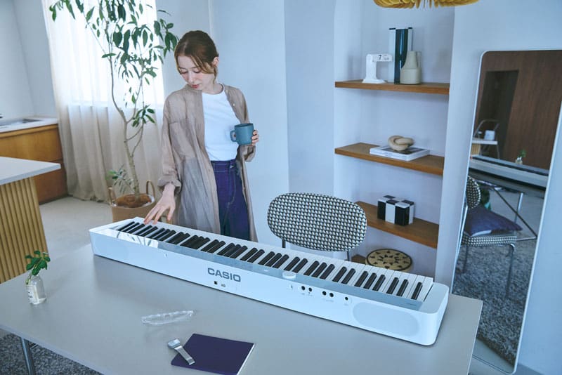 An image of a person standing near the piano and placing their hand on it